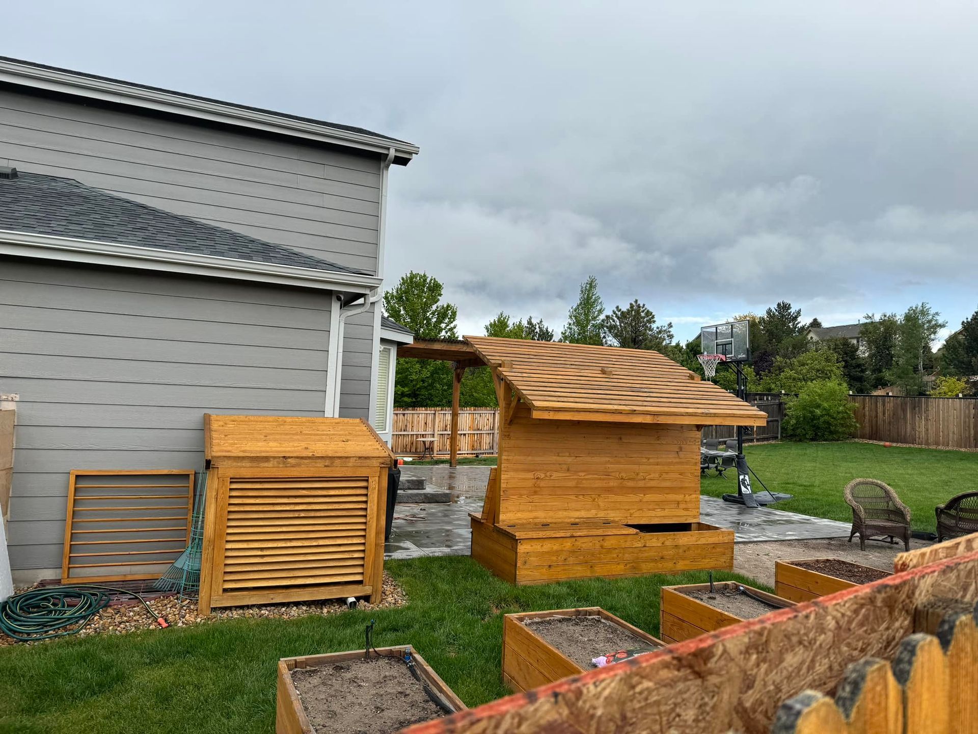 A backyard with a wooden shed and a basketball hoop.