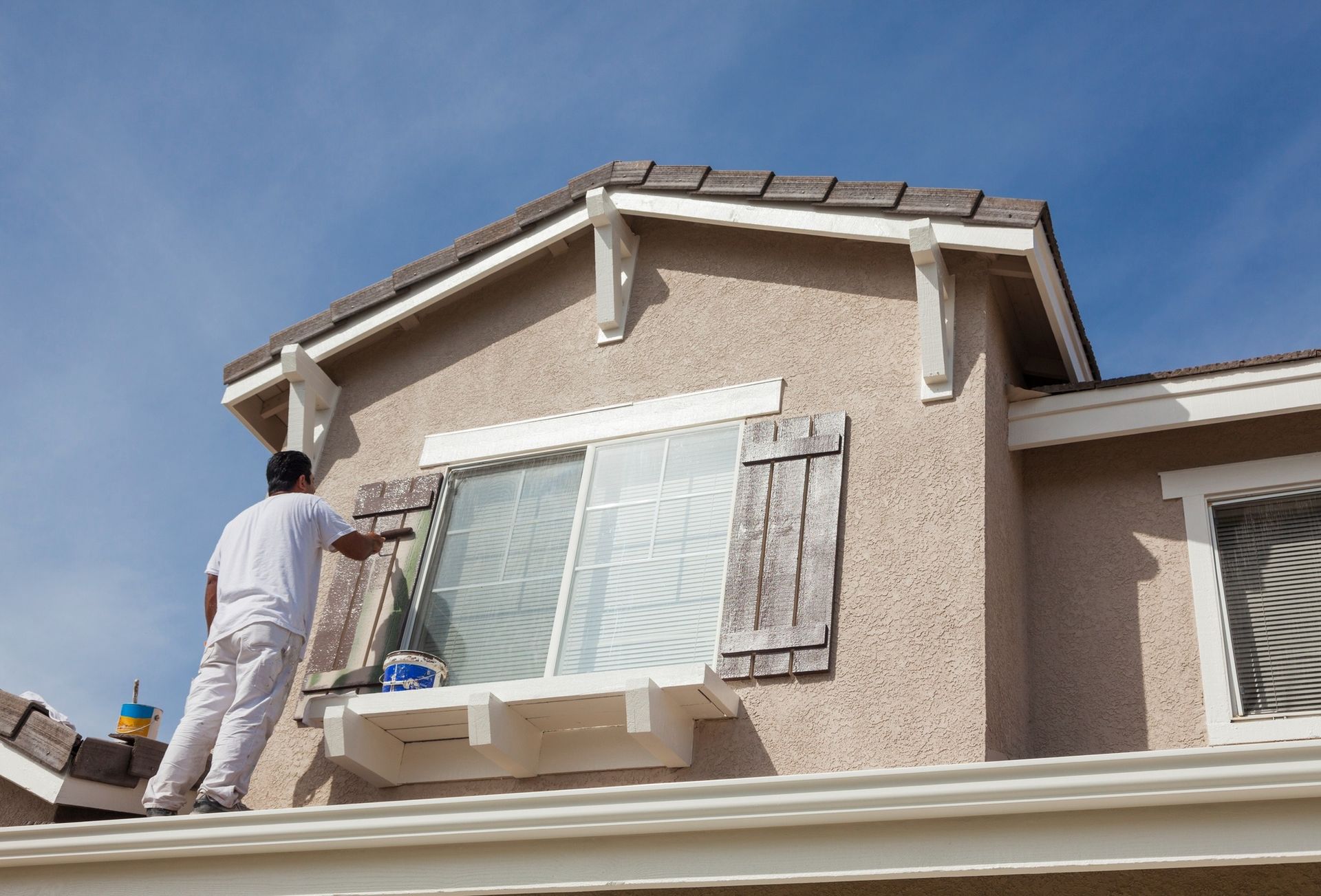 A man is painting the side of a house.