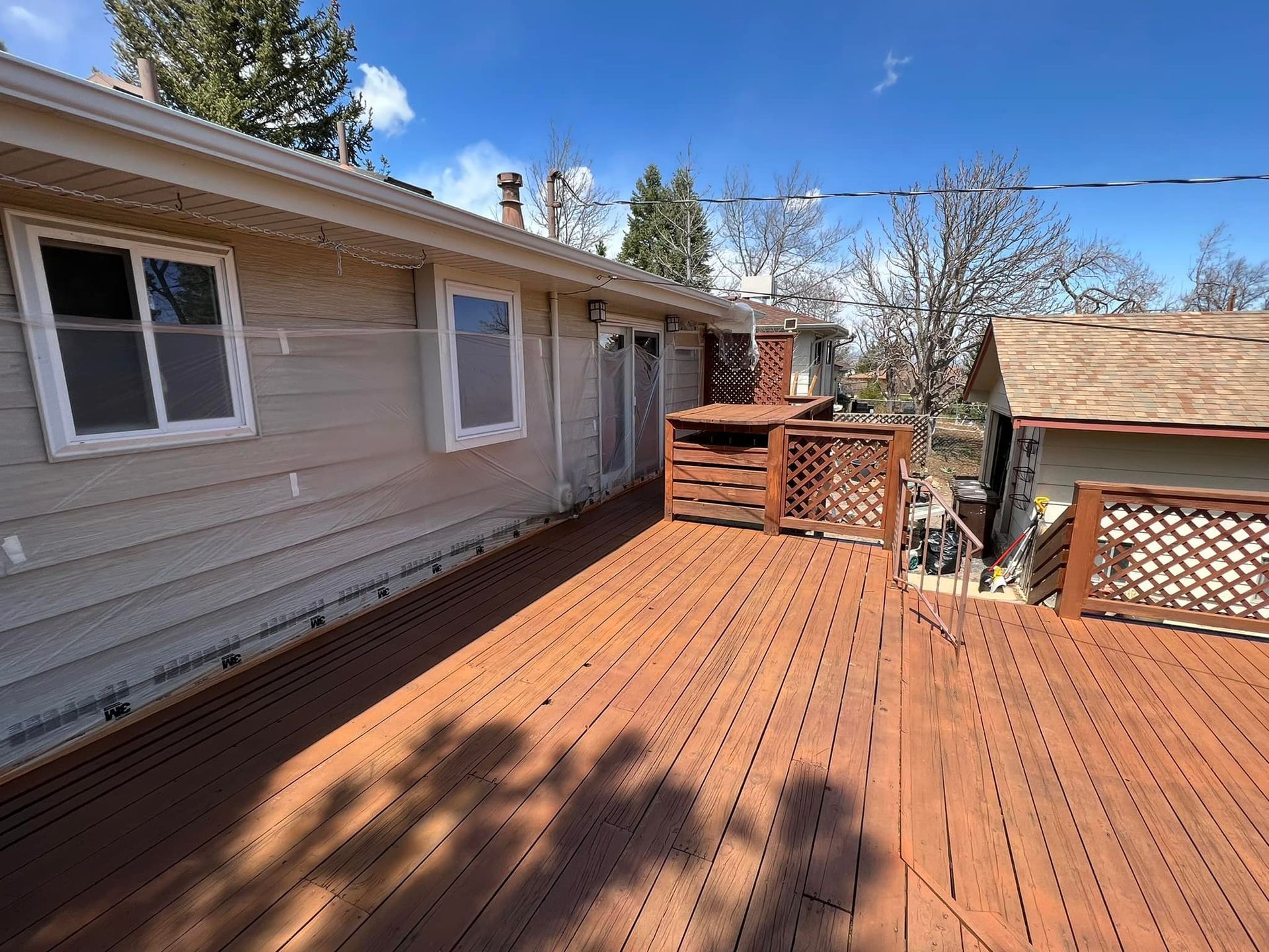 There is a large wooden deck in front of a house.