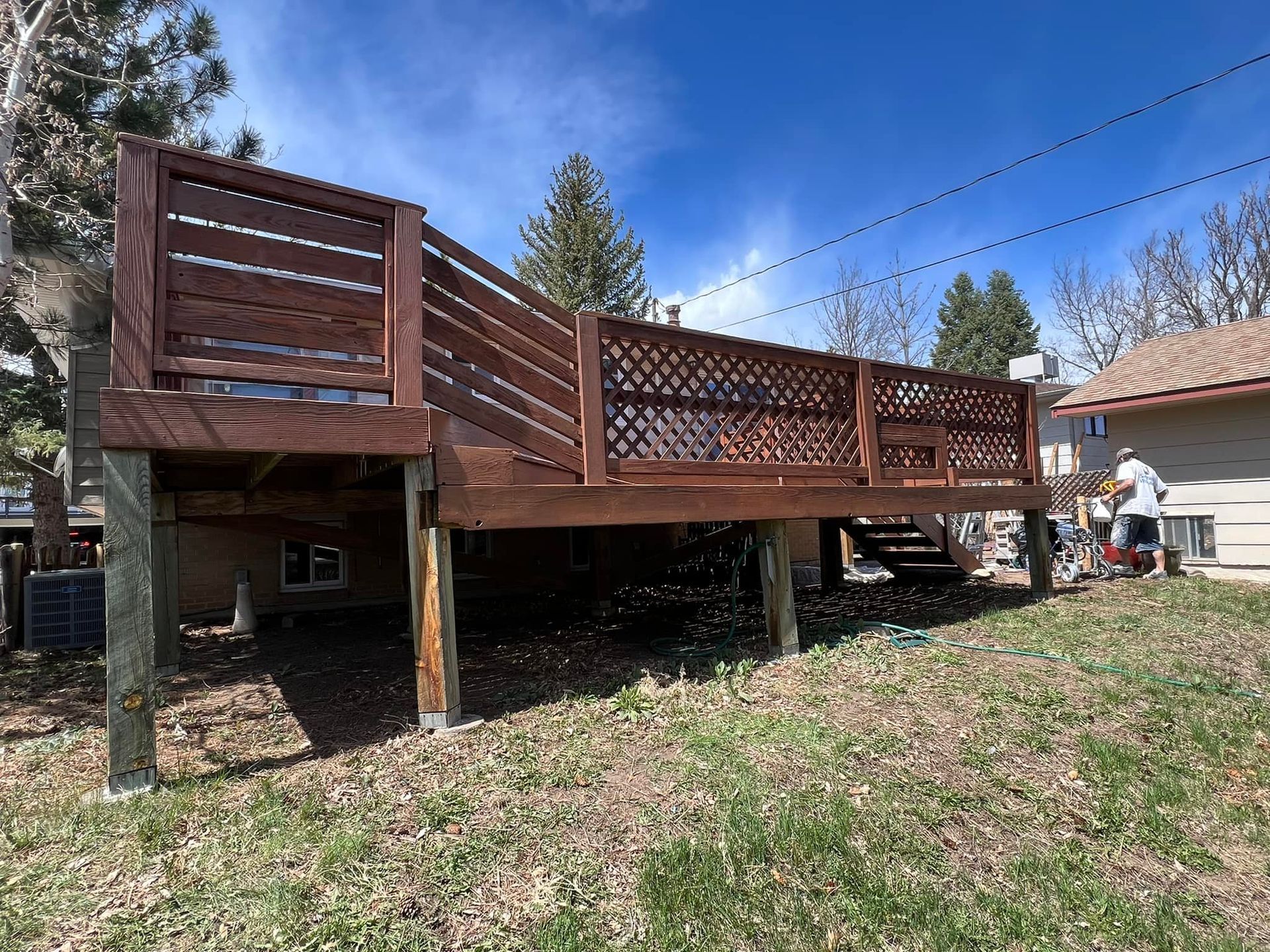 A wooden deck is in the backyard of a house.