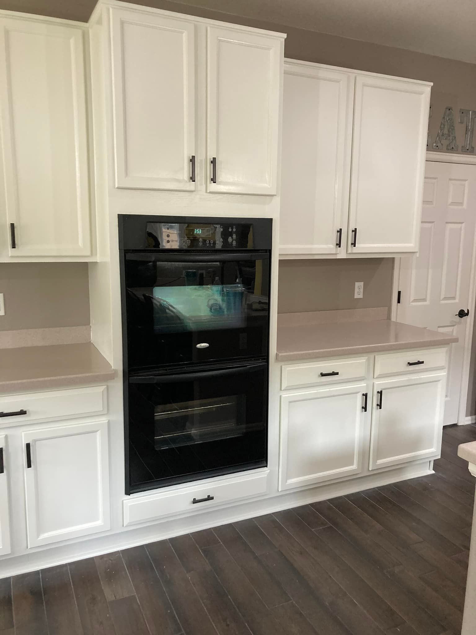 A kitchen with white cabinets and a black oven.