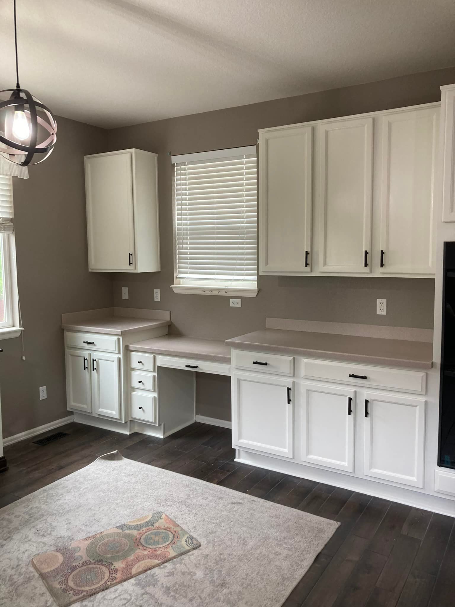 A kitchen with white cabinets and a desk in the corner.