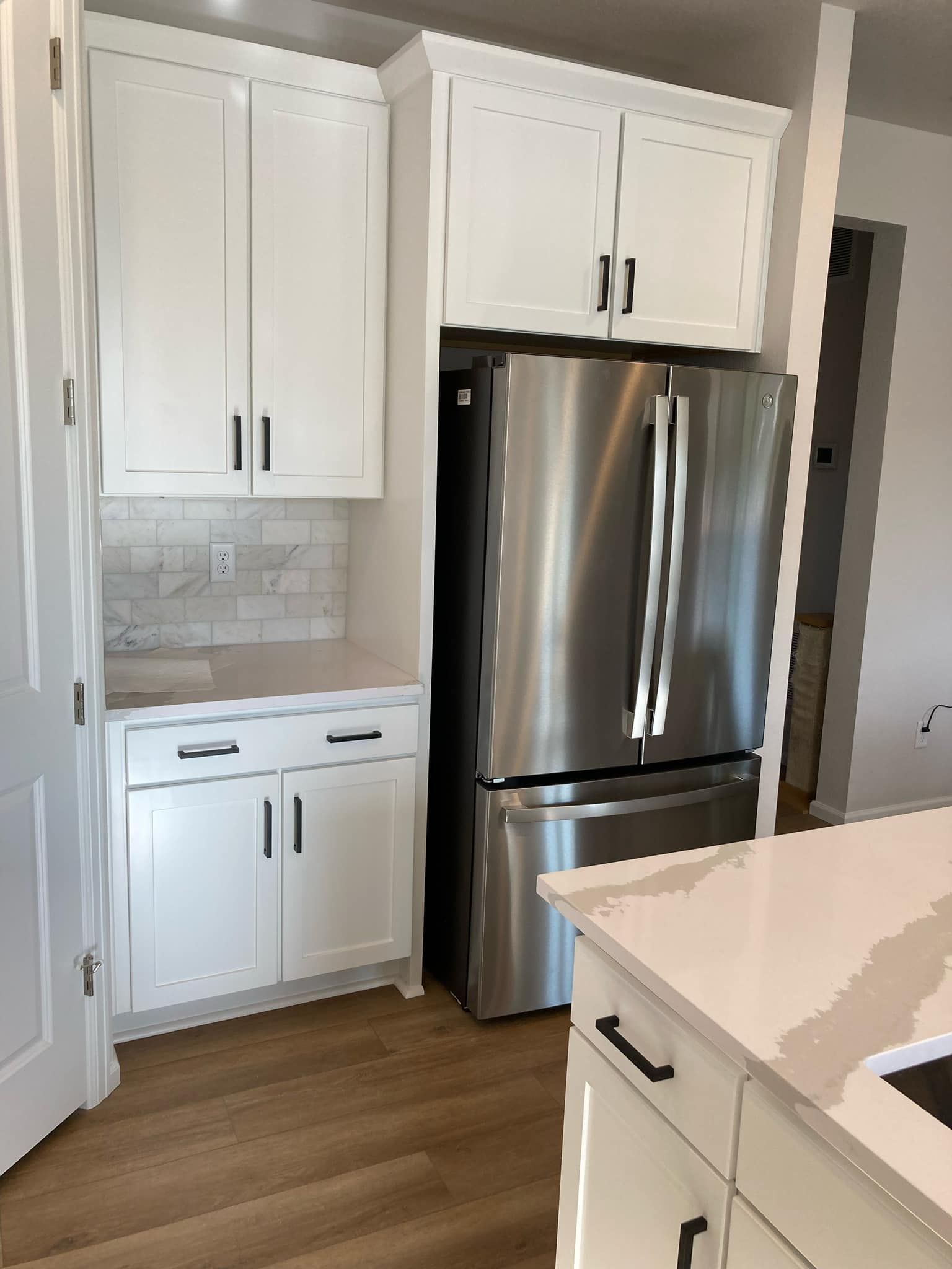 A kitchen with white cabinets and a stainless steel refrigerator