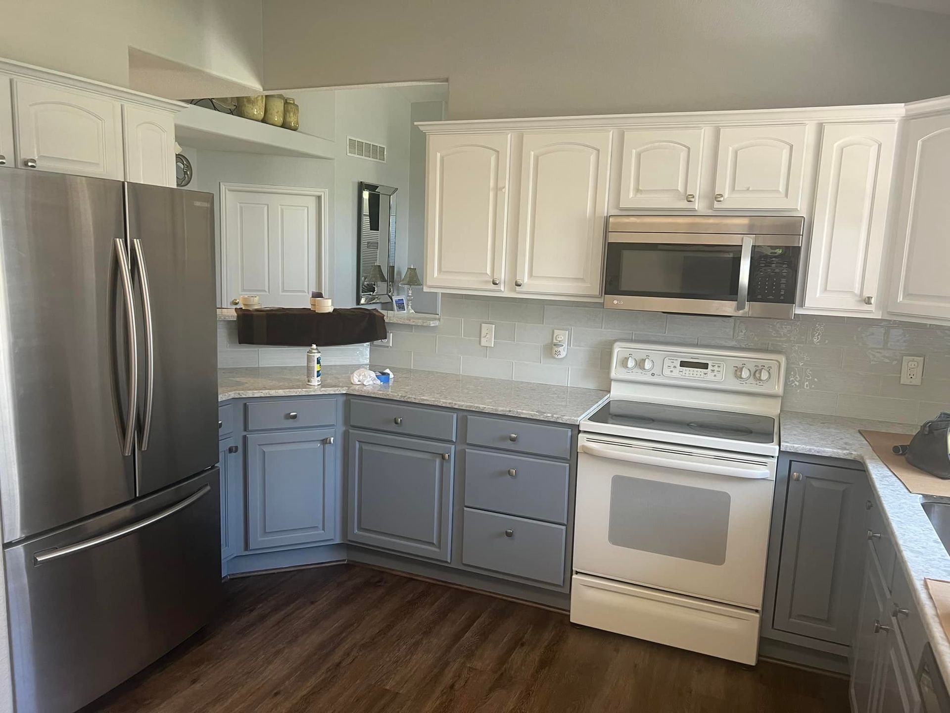 A kitchen with white cabinets , stainless steel appliances , a stove , refrigerator and microwave.