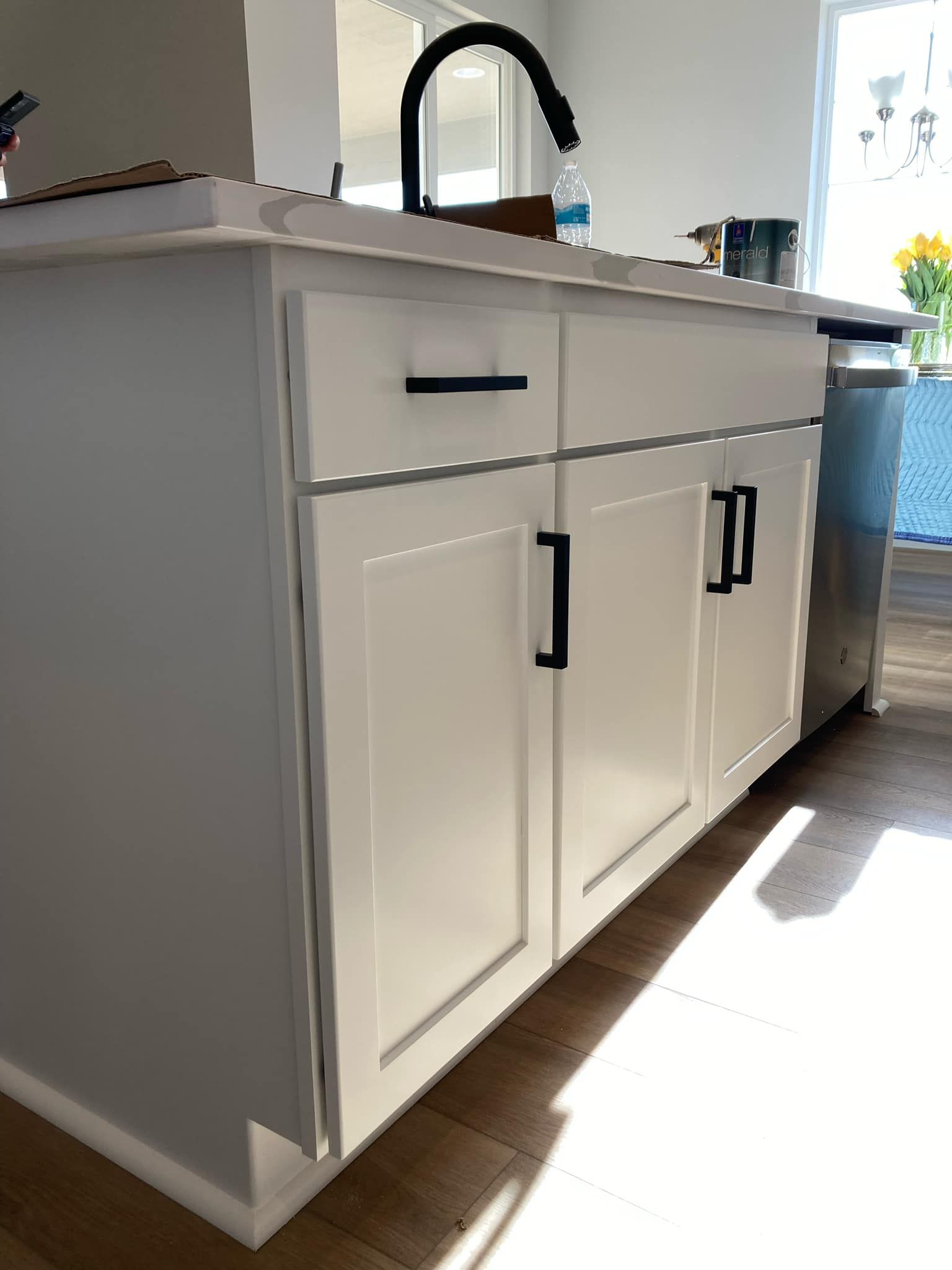 A kitchen with white cabinets , a sink , and a dishwasher.