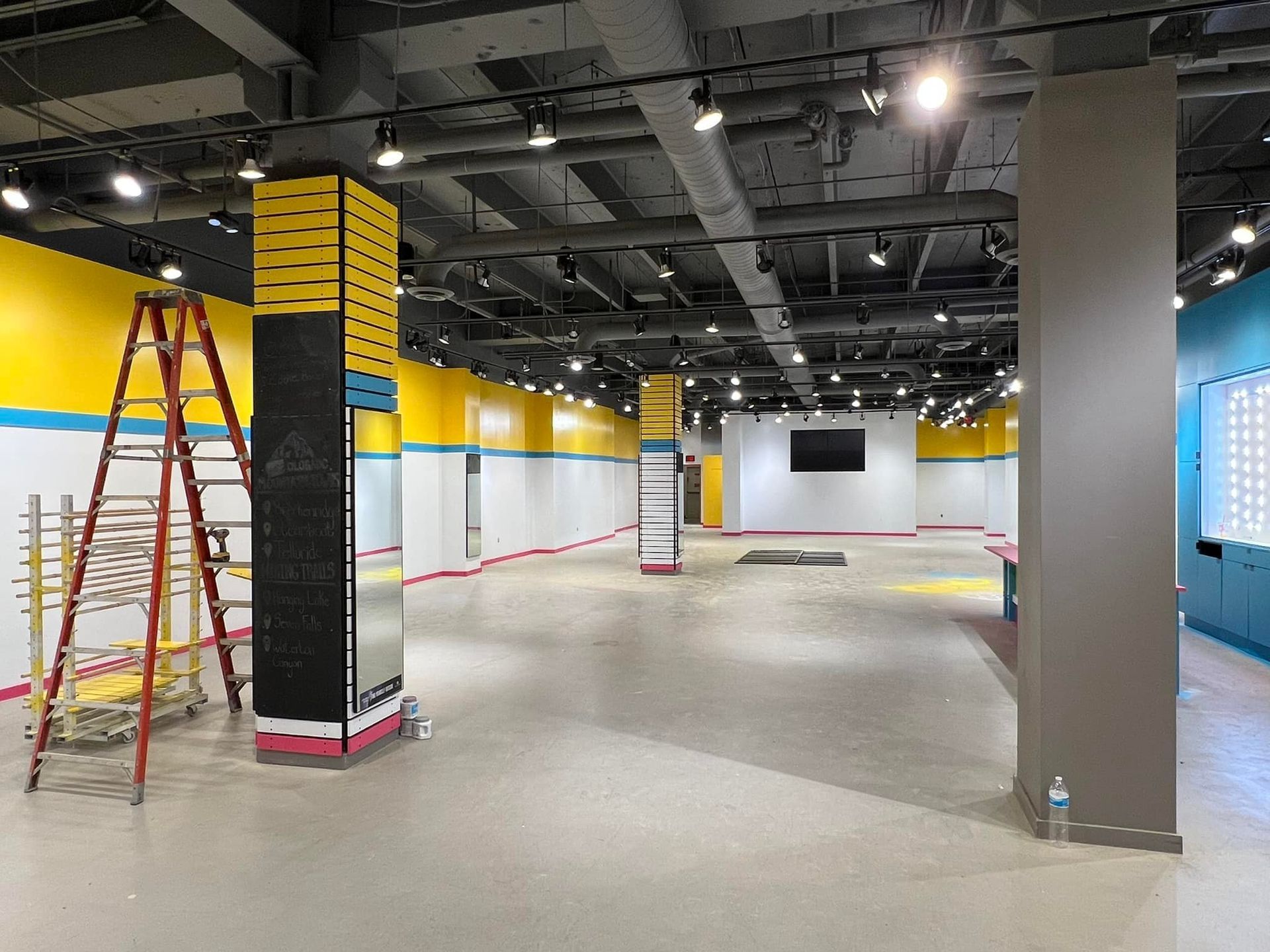 A large empty room with a ladder in the middle of it.