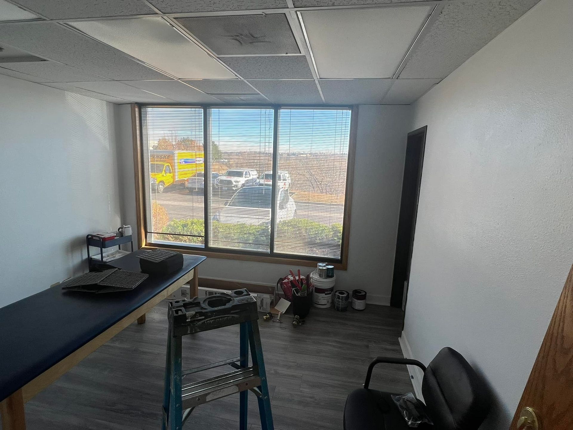 A room with a table , chair , ladder and window.