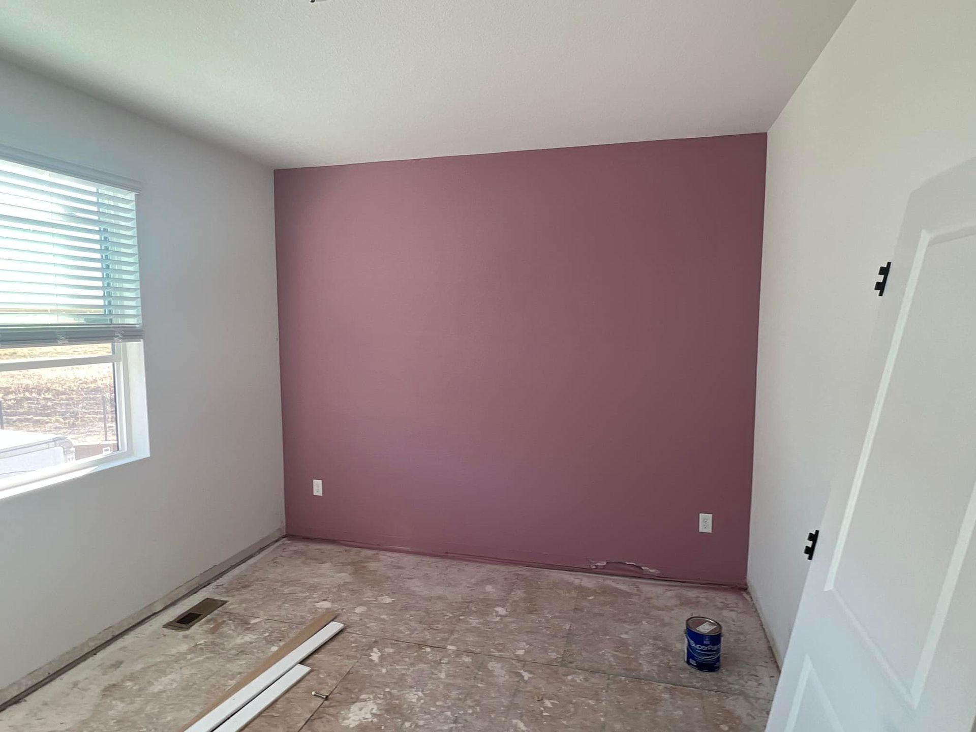 A room with a purple wall and a window.