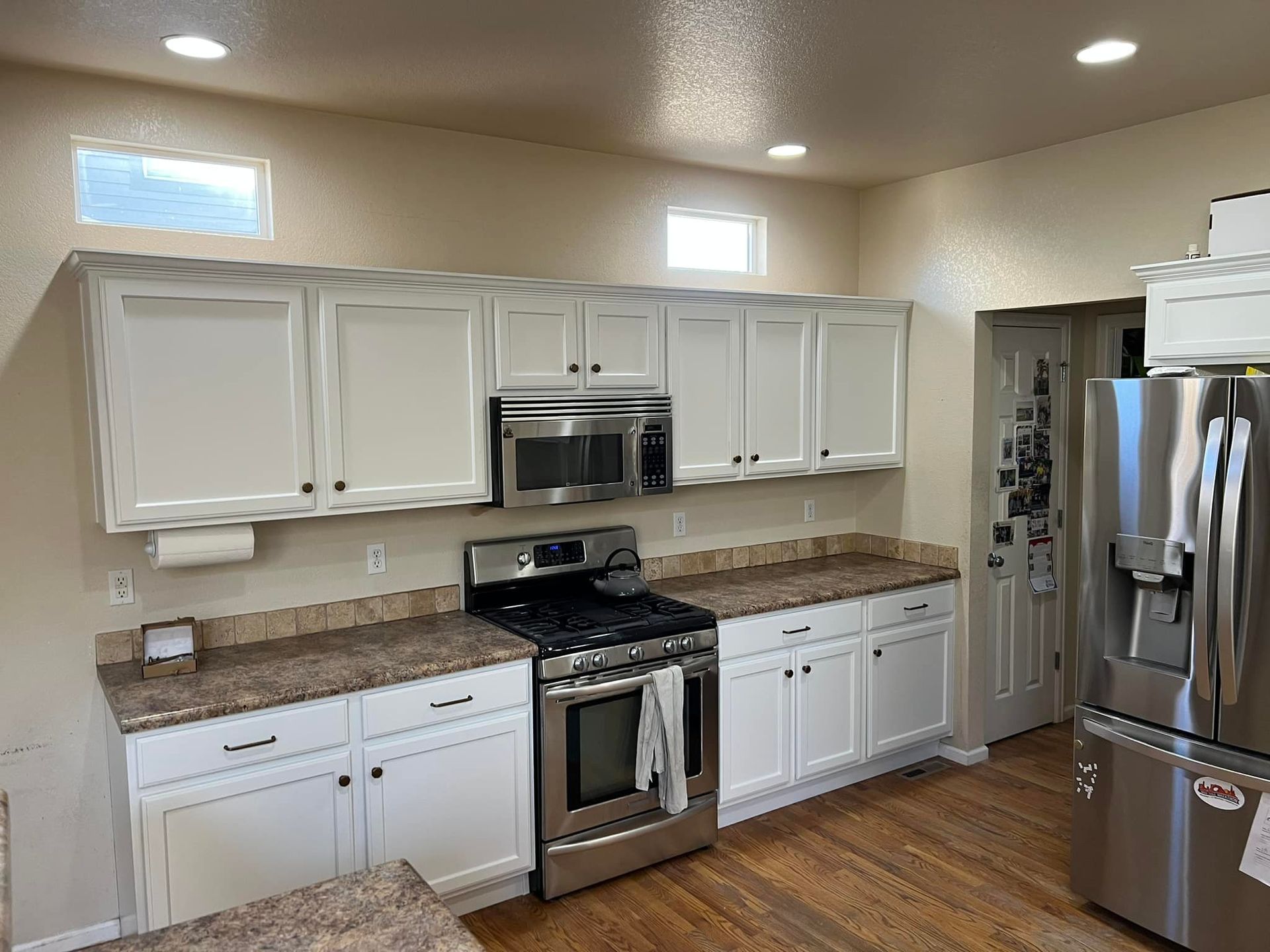 A kitchen with white cabinets , stainless steel appliances , and granite counter tops.