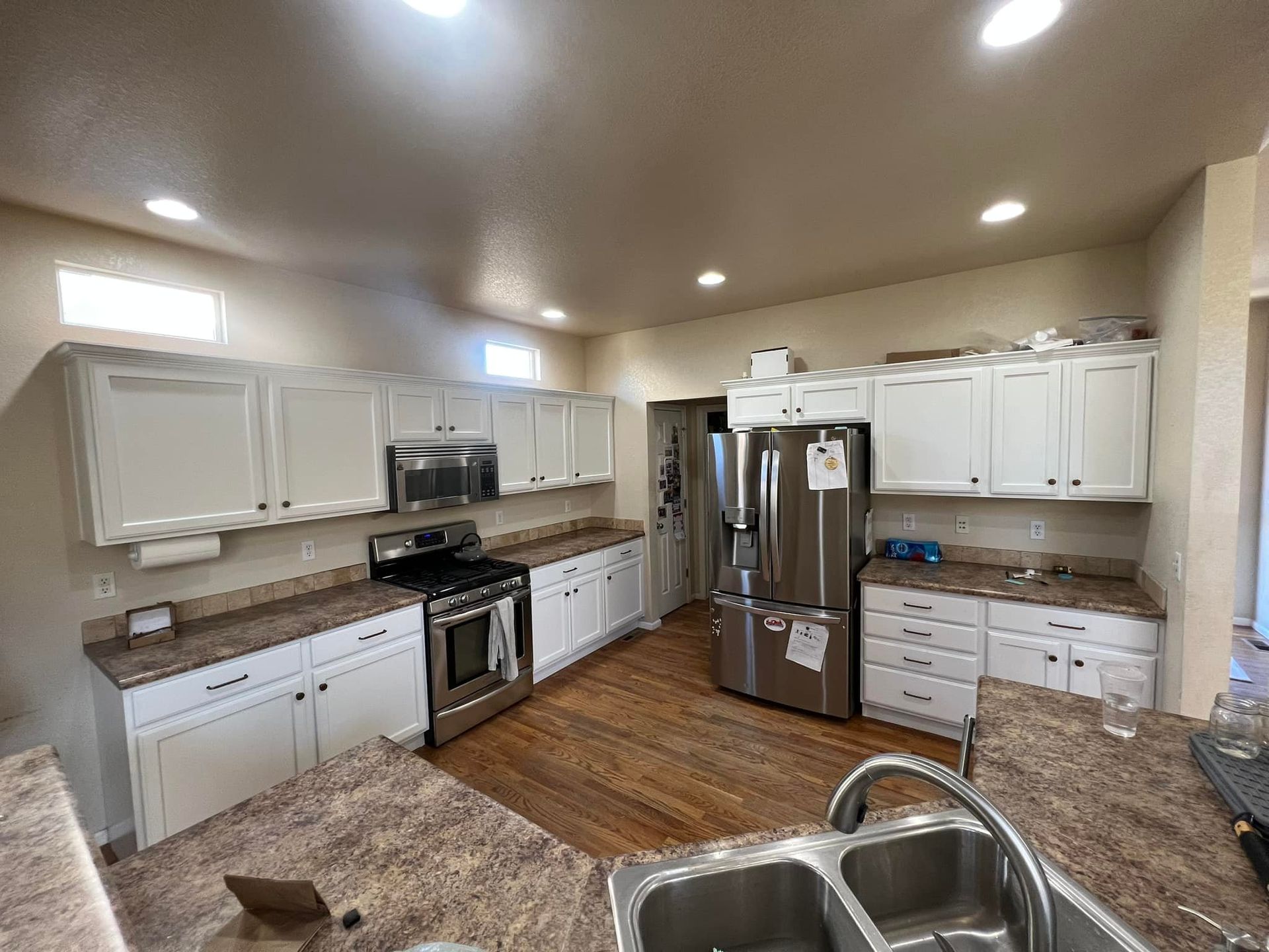 A kitchen with white cabinets , granite counter tops , stainless steel appliances and a sink.