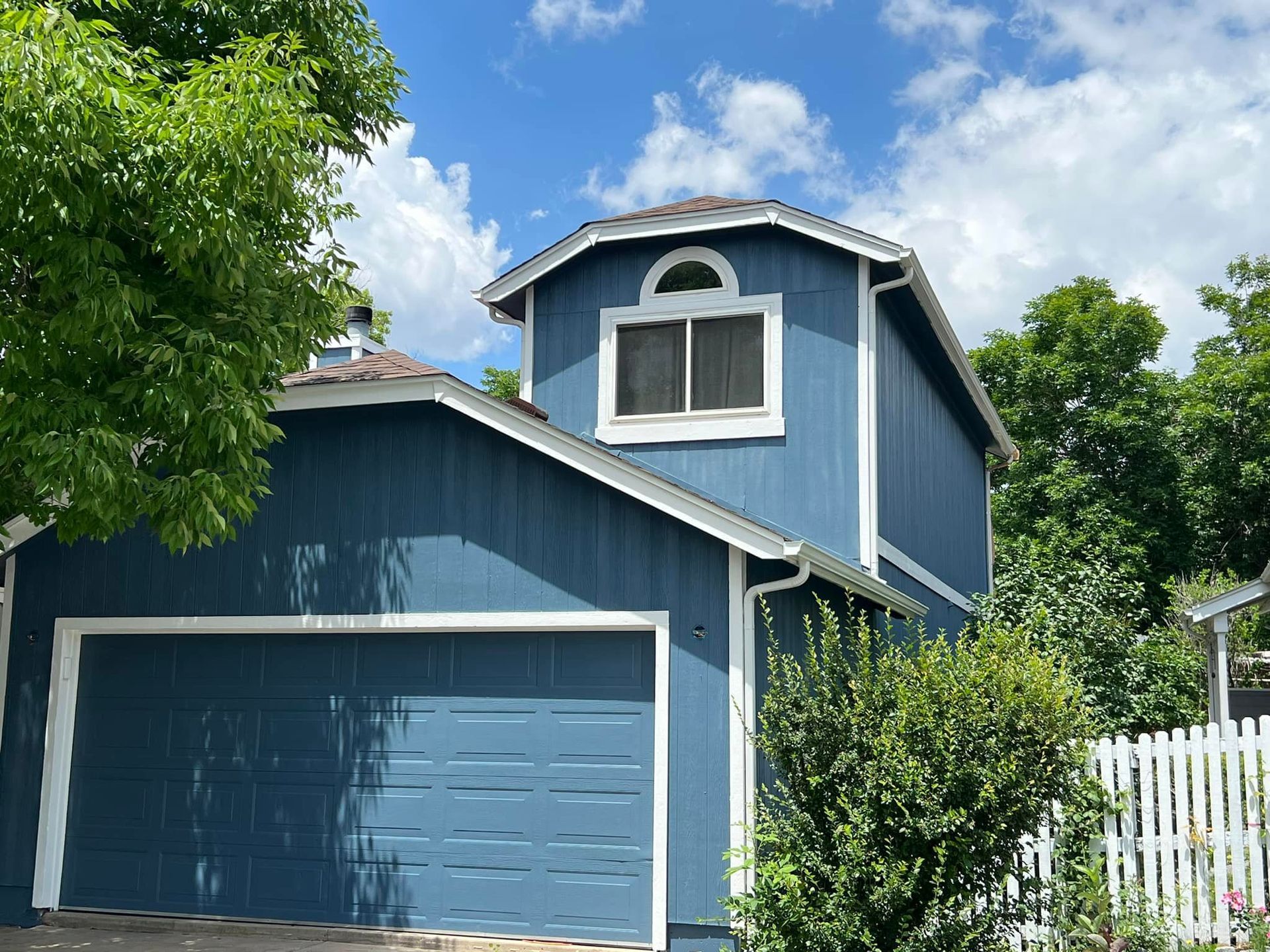 A blue house with a white trim and a garage door