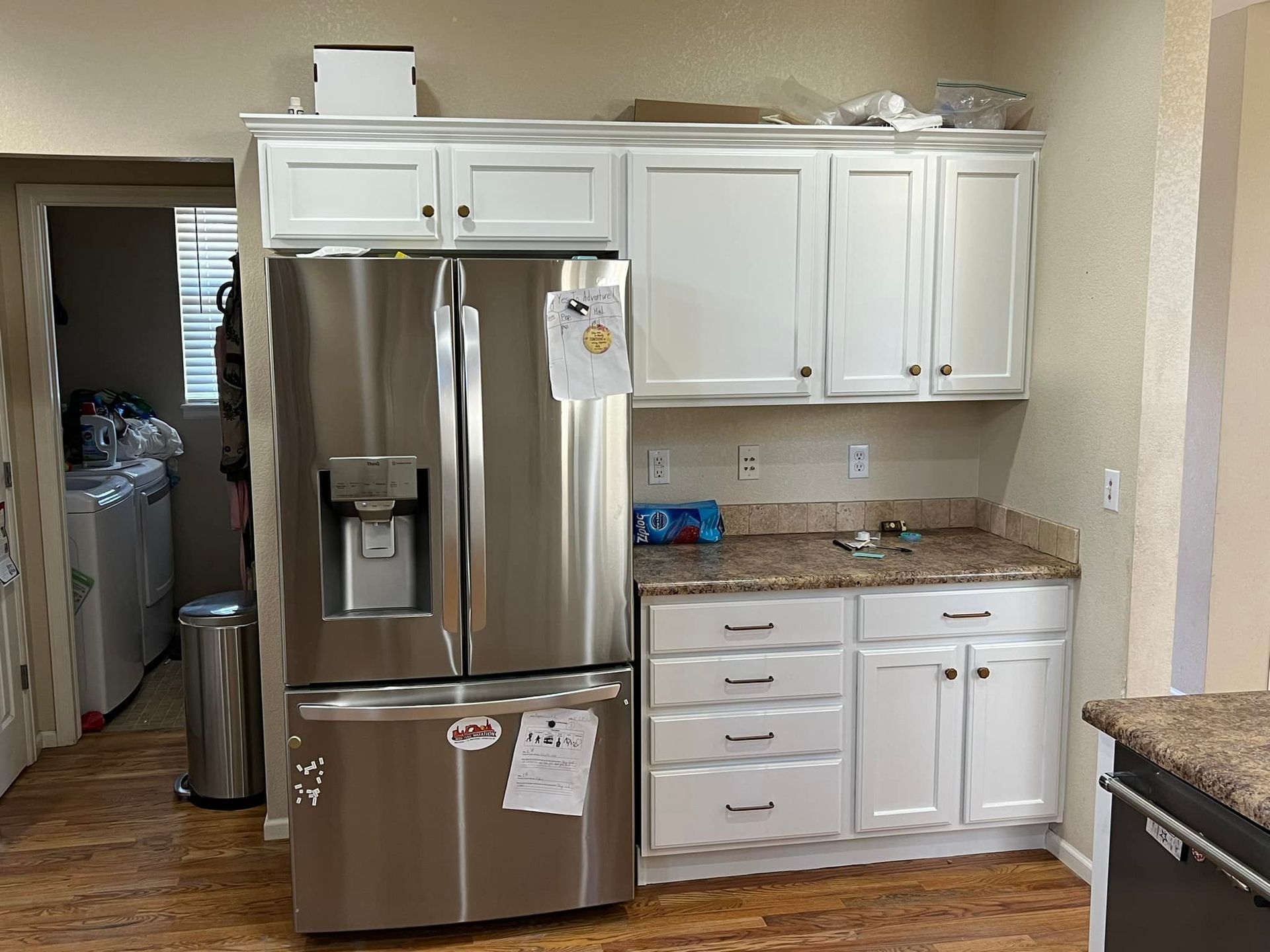 A kitchen with white cabinets and a stainless steel refrigerator