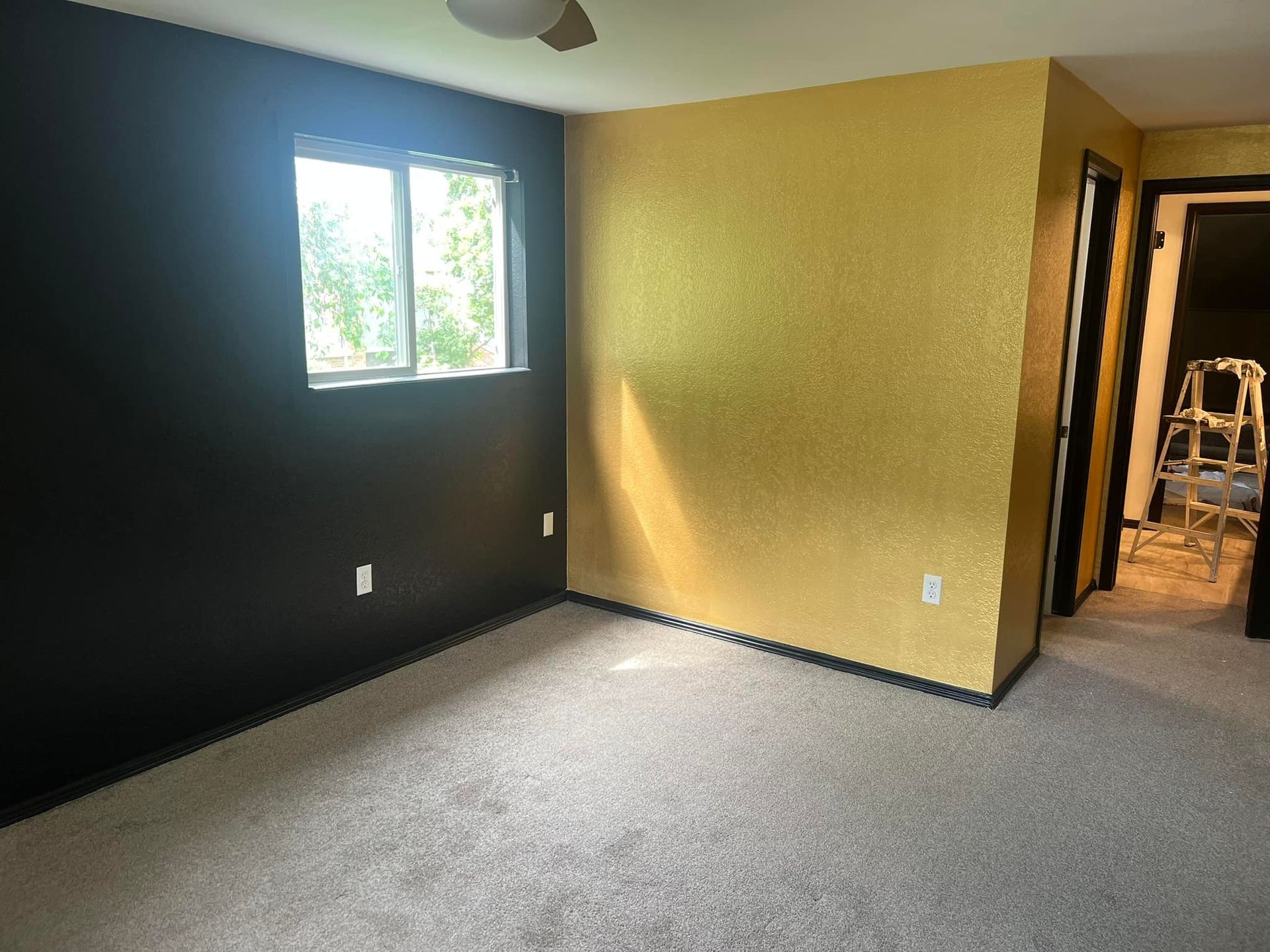 An empty room with a window and a ceiling fan.