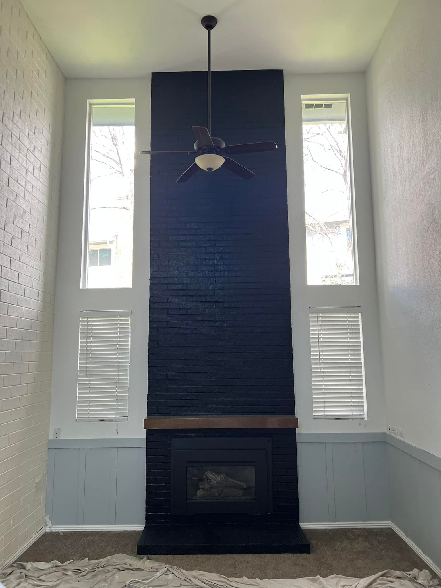 A living room with a fireplace and a ceiling fan.