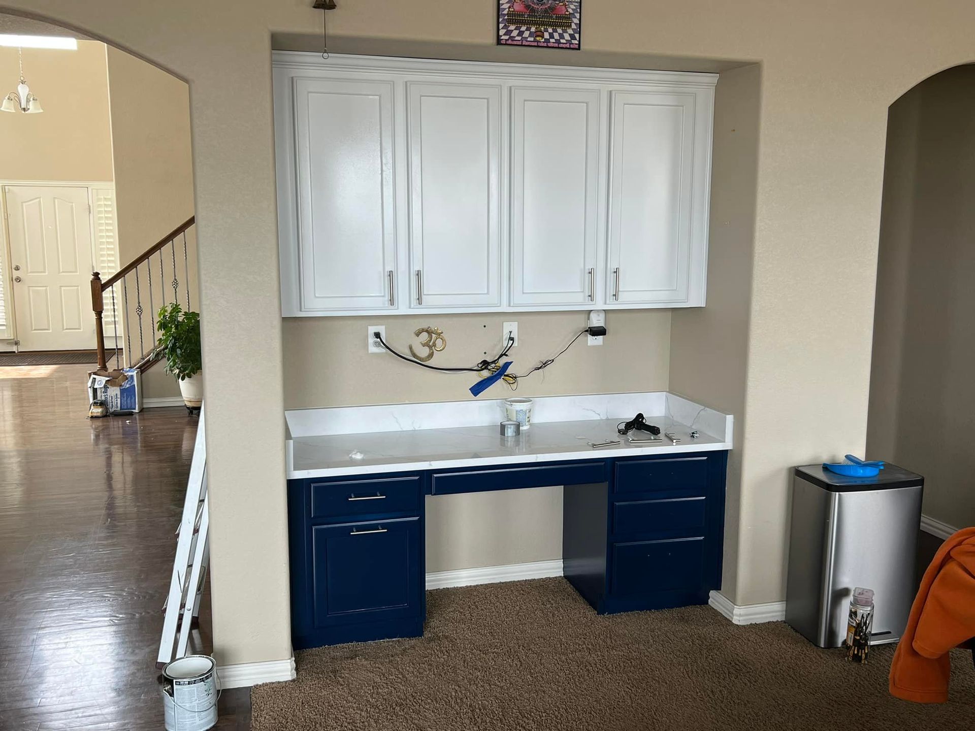 A room with a desk and white cabinets in it