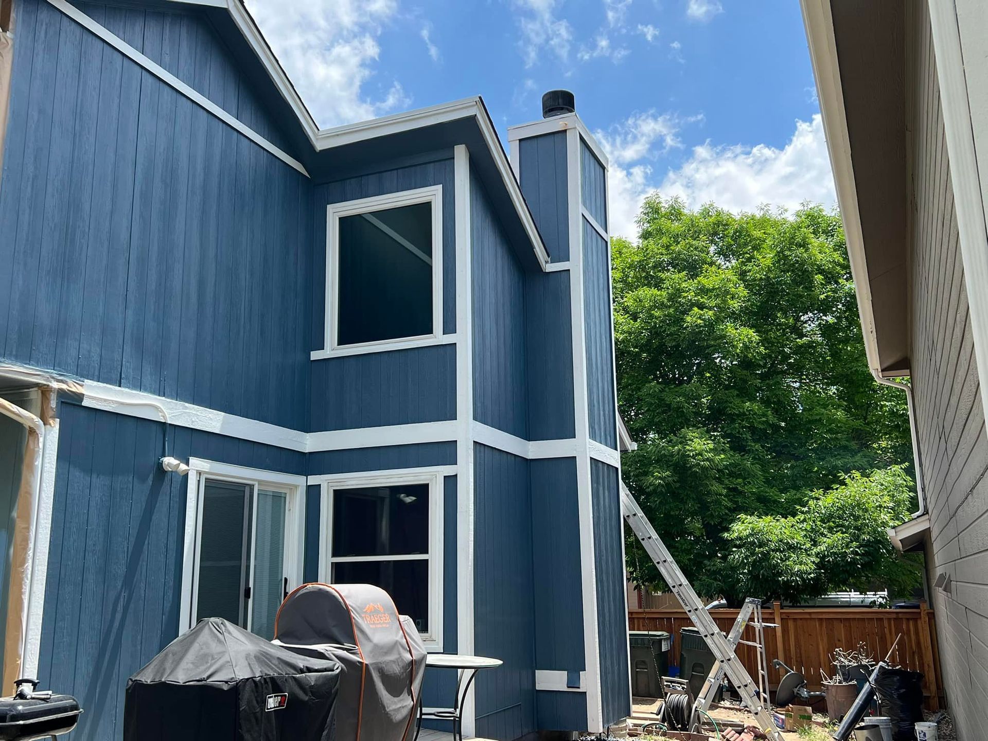 A blue house with white trim is being painted.