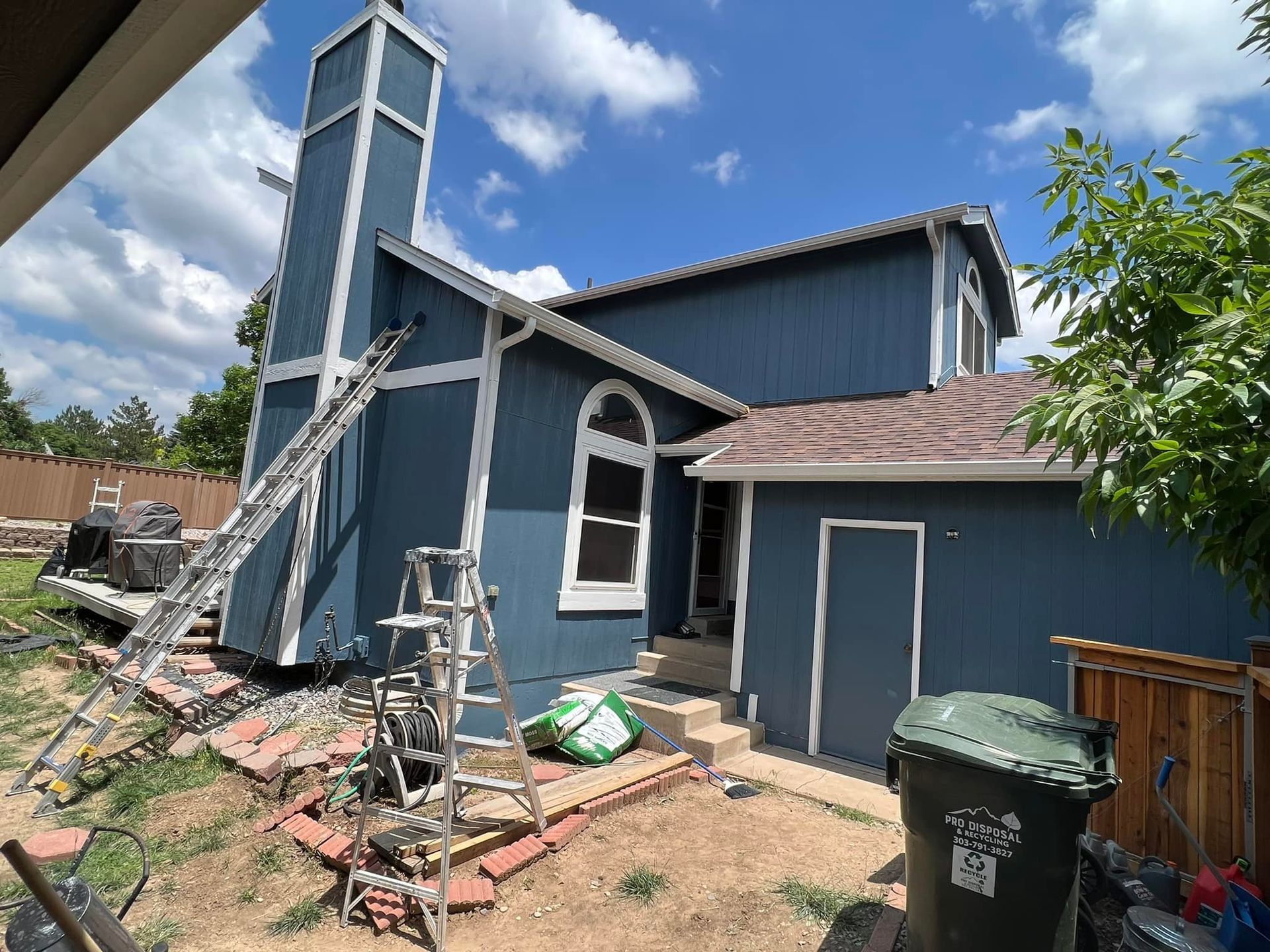 A blue house with white trim is being painted.