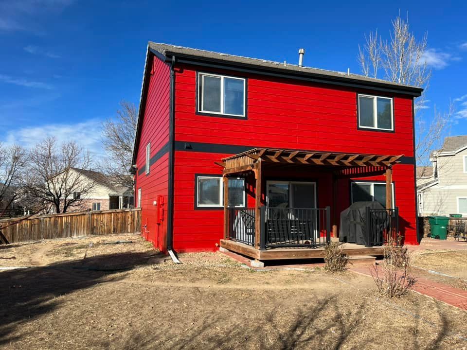 A red house with a deck and a pergola in the backyard.