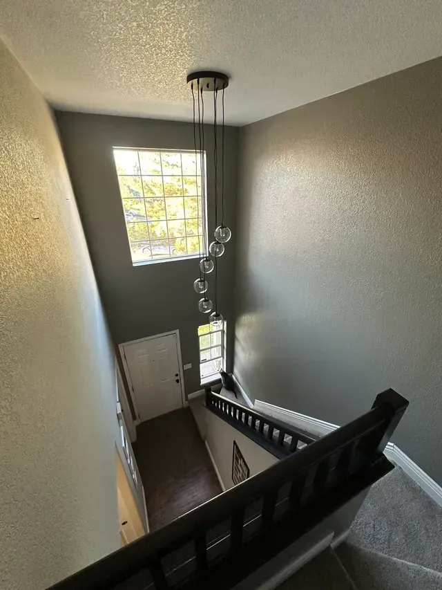 An aerial view of a staircase with a chandelier hanging from the ceiling.
