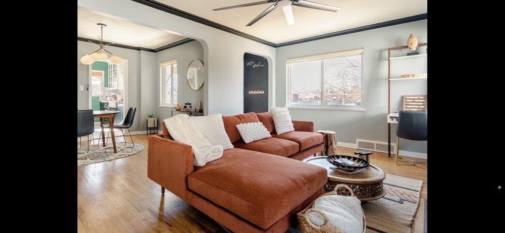 A living room with a couch , ottoman , coffee table and ceiling fan.