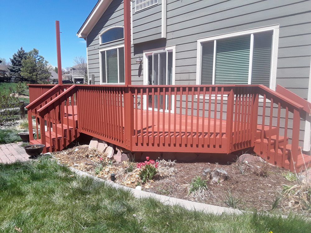 A house with a red deck and stairs in front of it