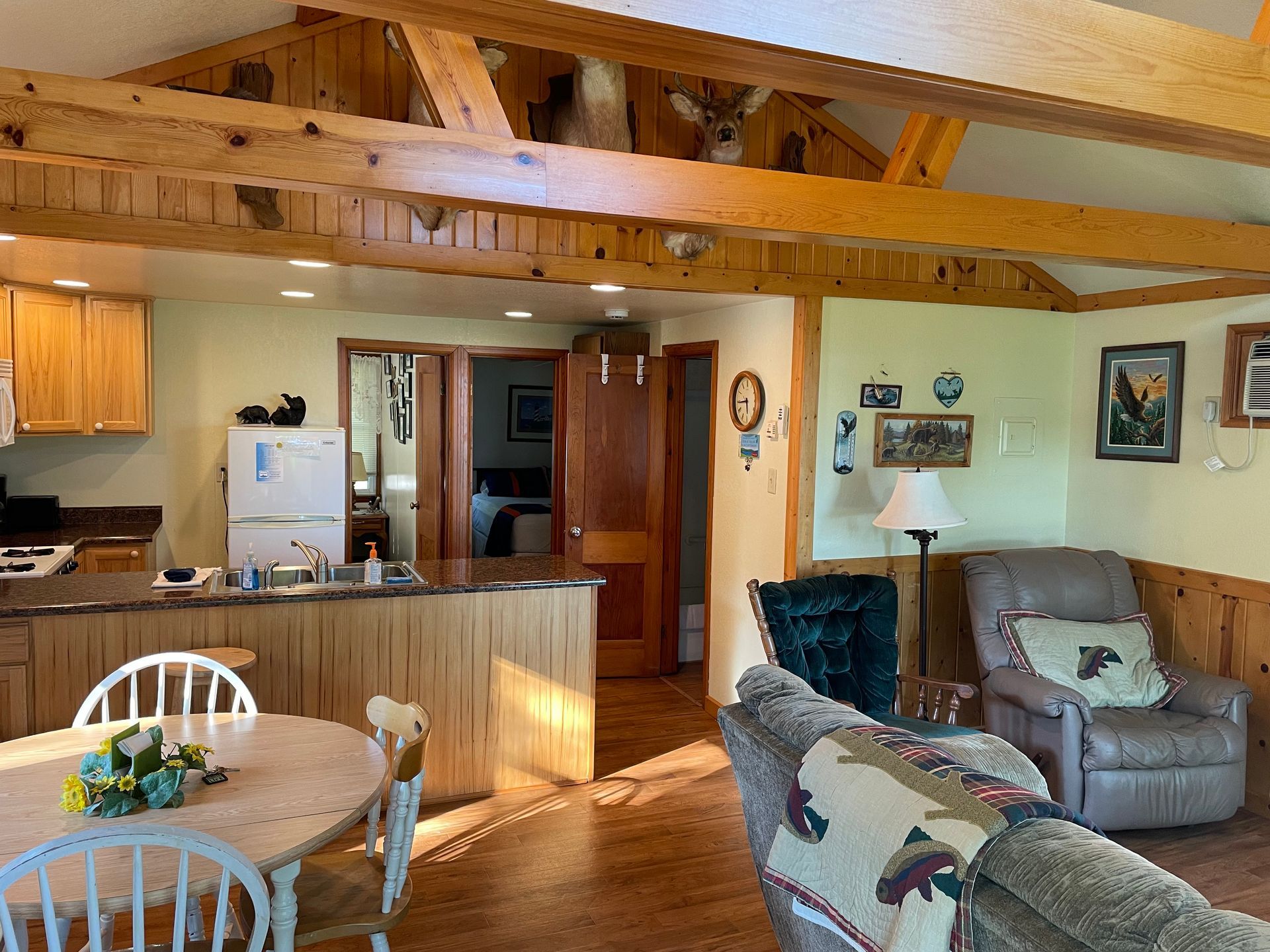 A living room with a table , chairs , and a refrigerator.