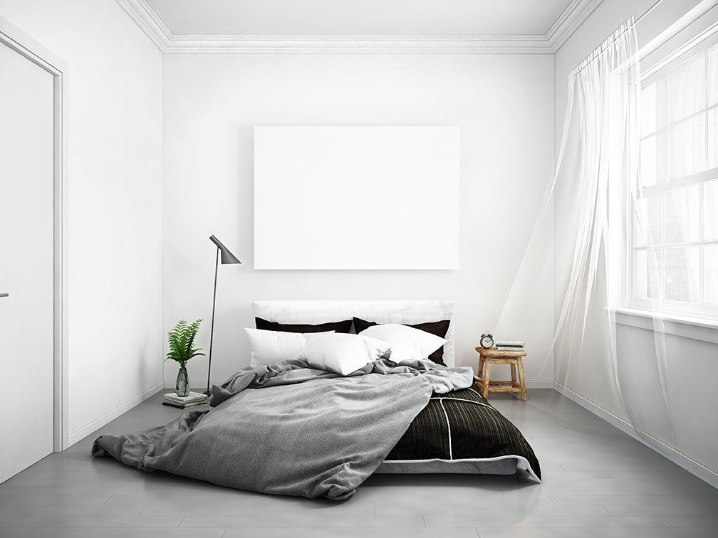 Quarto minimalista com cama, obras de arte em branco e cortinas transparentes.
