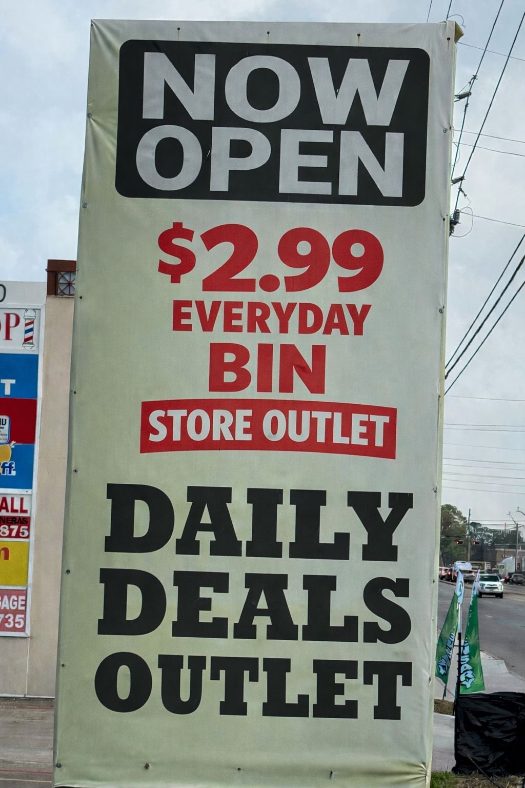 A tall, white vertical banner sign advertises 
