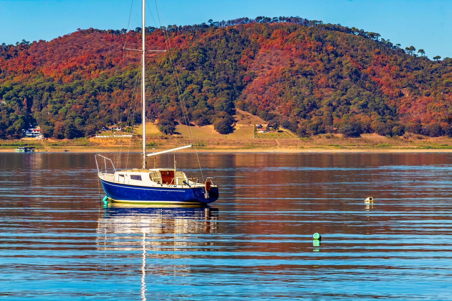 A sailboat is floating on a lake with mountains in the background.
