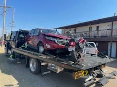 A red car is being towed by a tow truck.