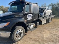 A tow truck is towing a car in a dirt field.