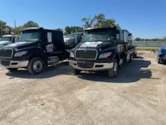 Two tow trucks are parked next to each other in a parking lot.