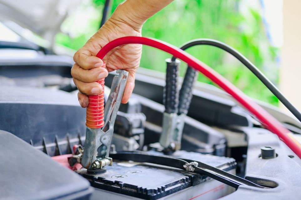 A person is charging a car battery with a jump starter.