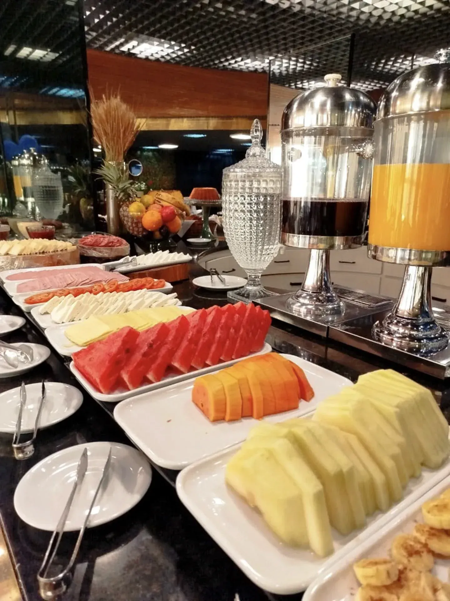 Prateleiras com mercadorias em uma loja, incluindo artigos de vidro, cachecóis e itens decorativos.