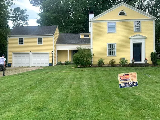 Yellow house with blue door and attached garage, in front of green lawn.