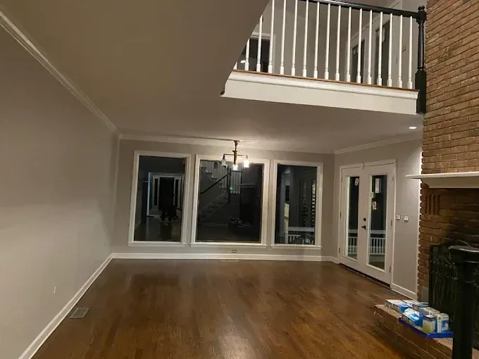 Living room with large windows, fireplace, and balcony; hardwood floors.