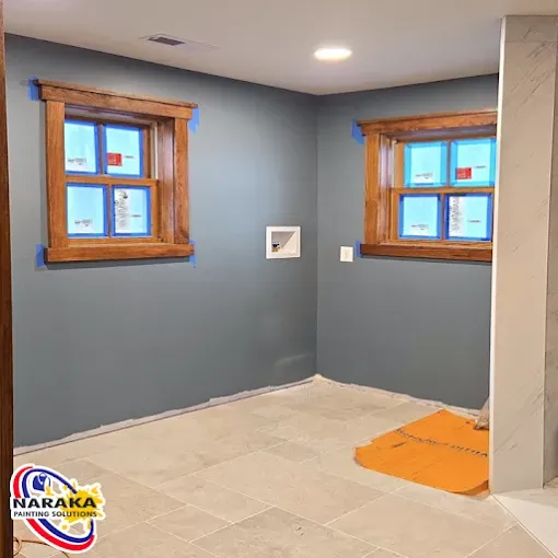 Room with blue walls, two wood-framed windows, and light-colored tile flooring.