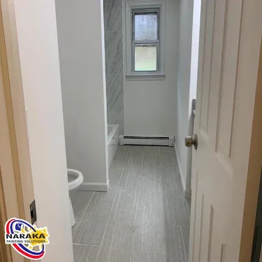 Empty bathroom with gray tiled floor, white walls, and a small window.