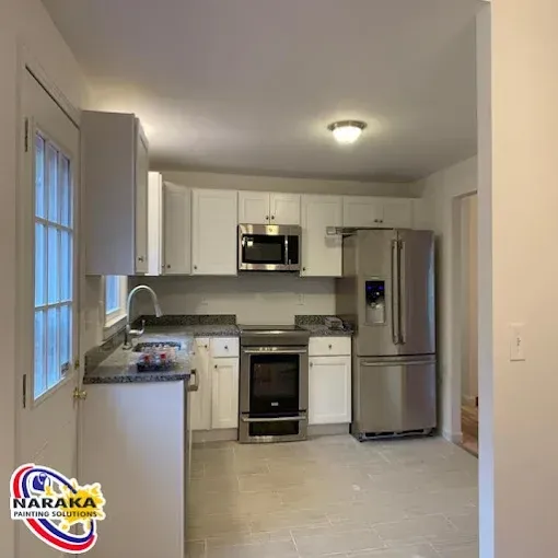 White kitchen with stainless steel appliances and granite countertops.