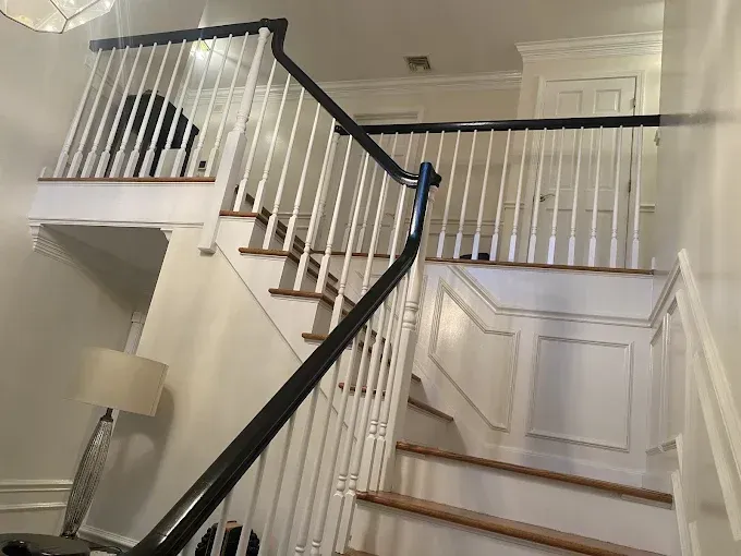 White staircase with black handrails; natural wood steps.