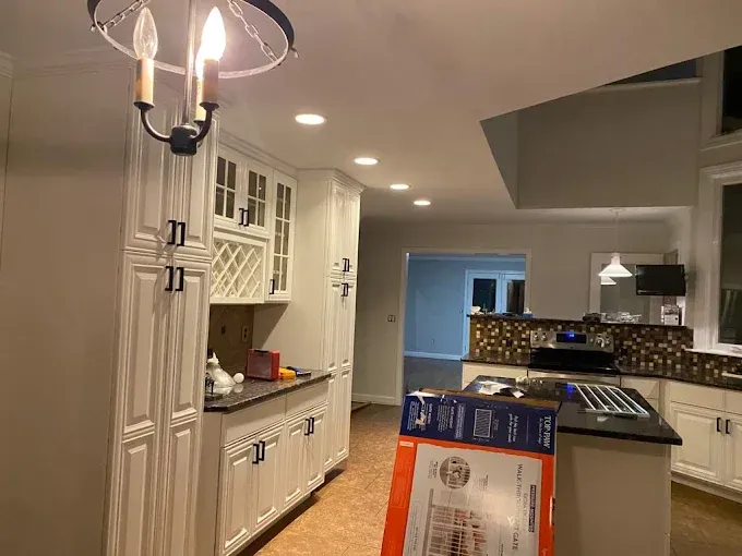 Kitchen with white cabinets, dark countertops, recessed lighting, and a chandelier.