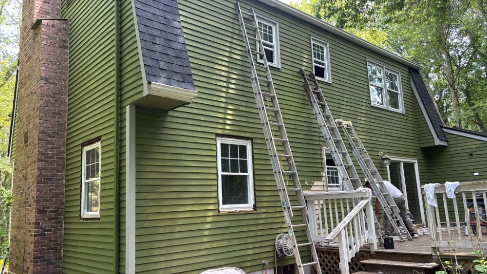 Green house siding, ladders against the wall, chimney.