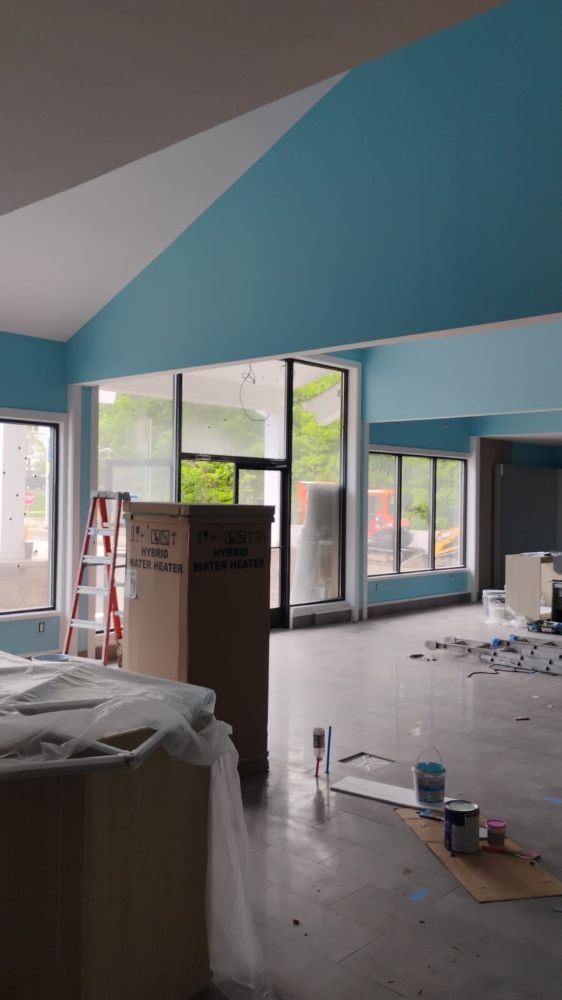 Interior room being painted, blue walls, white ceiling, glass windows, a cardboard box, and a ladder.