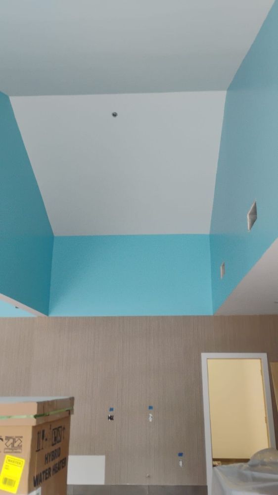 Interior shot: light blue and white painted ceiling and walls above a tan wall, an open door, and a brown box.