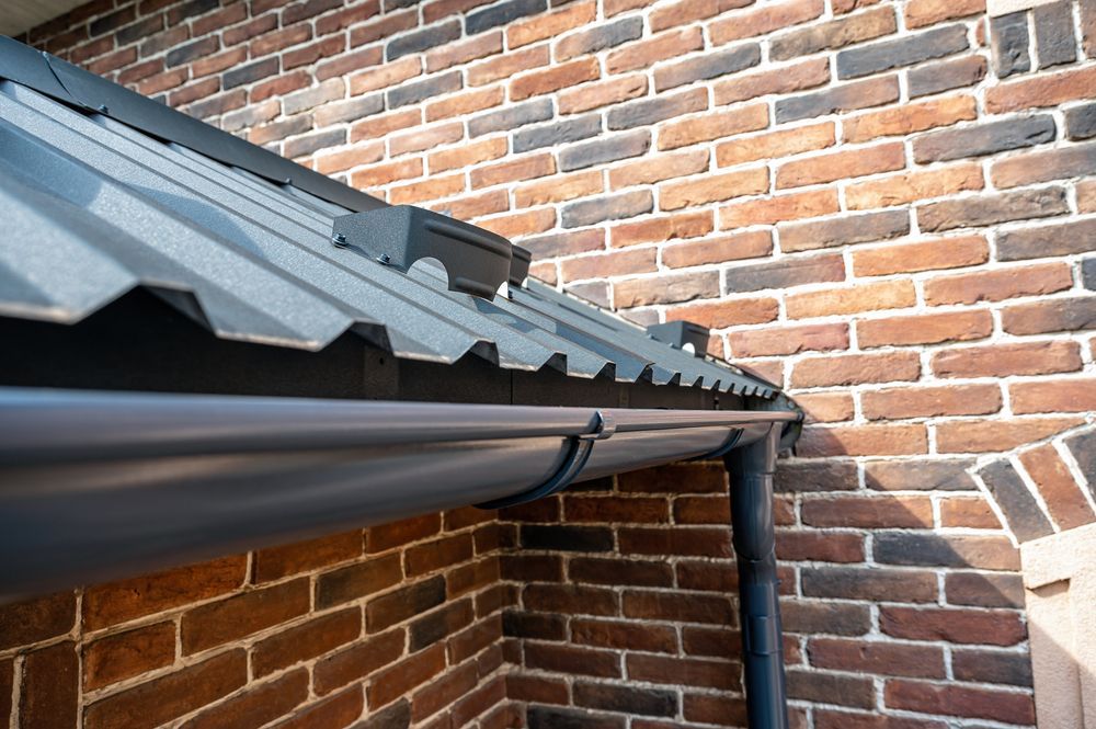A close up of a gutter on a brick wall.