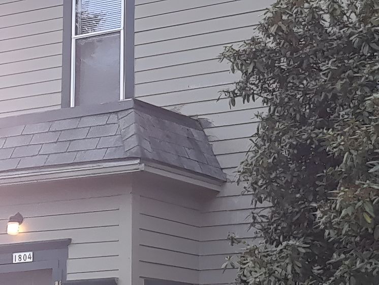 A house with a balcony and a tree in front of it.