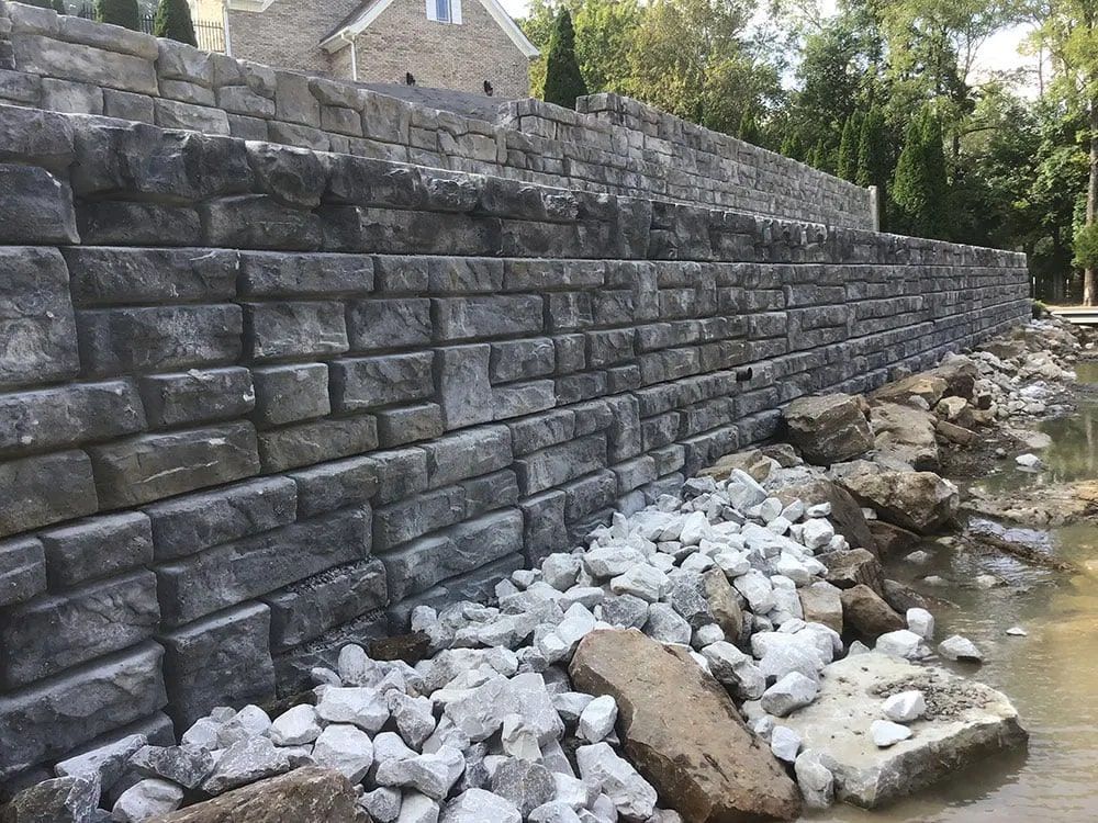 A large stone wall is being built next to a river.