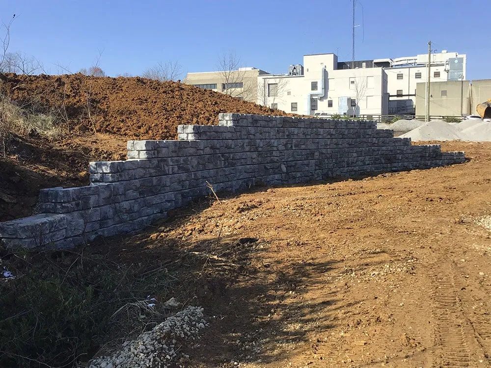 A large pile of bricks is sitting in the middle of a dirt field.