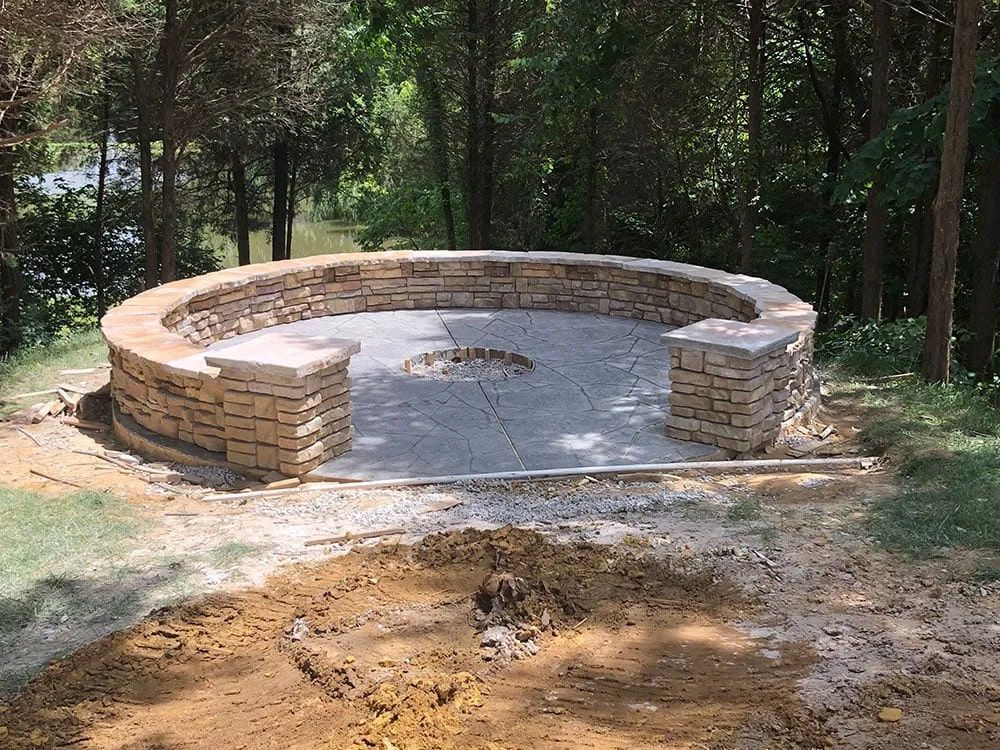 A fire pit is being built in the middle of a lush green forest.