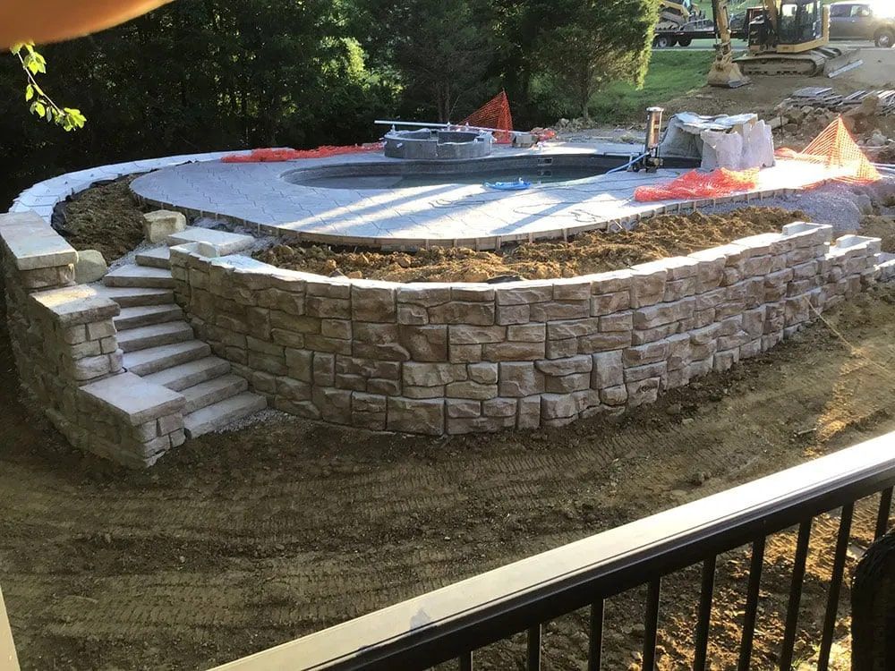 A swimming pool is being built next to a stone wall.